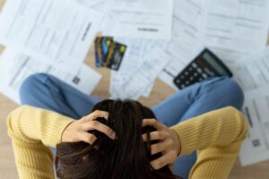 Photo with person sitting on the floor stressed out about debt bills and credit card bills.