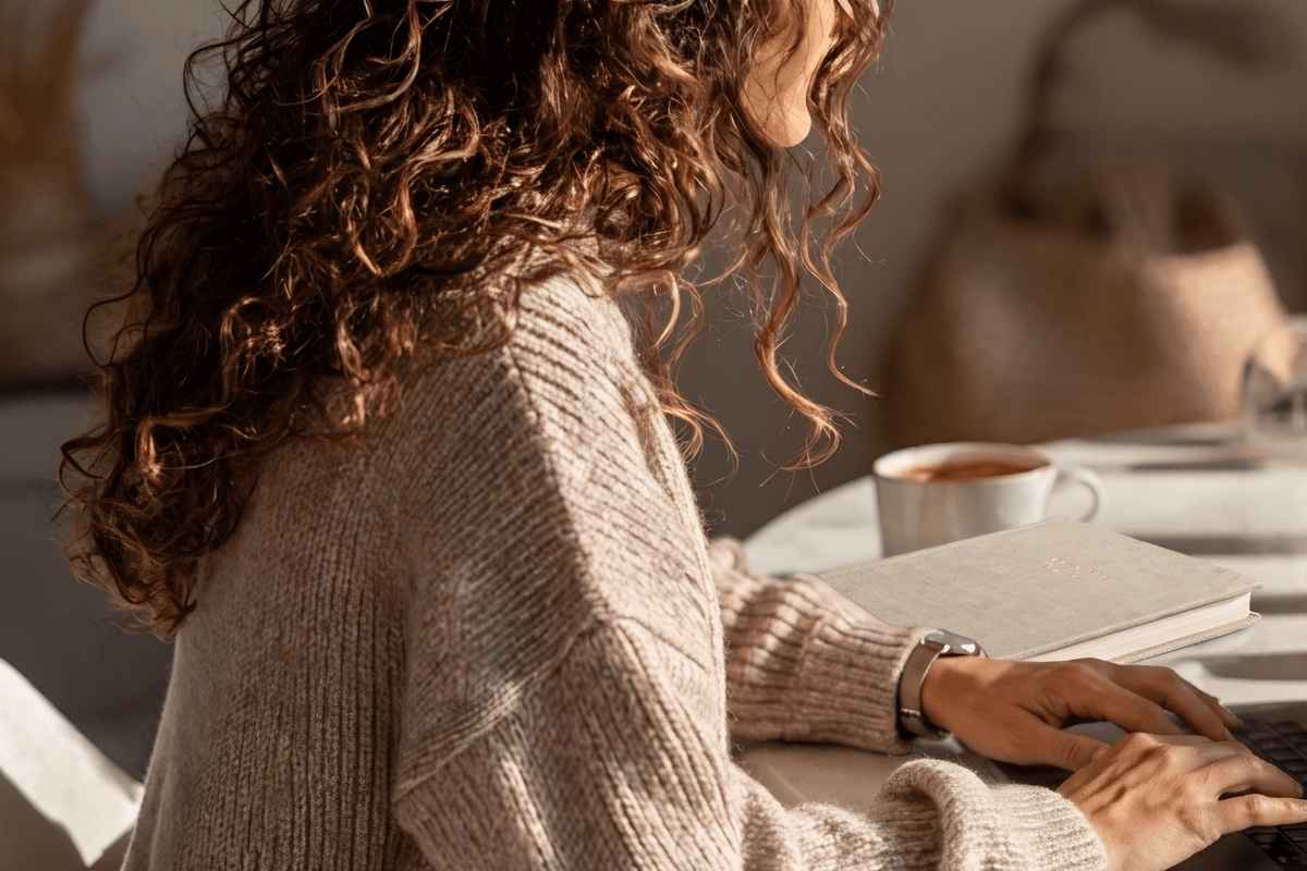 Woman working on a laptop with coffee and notebook while planning around lifestyle creep